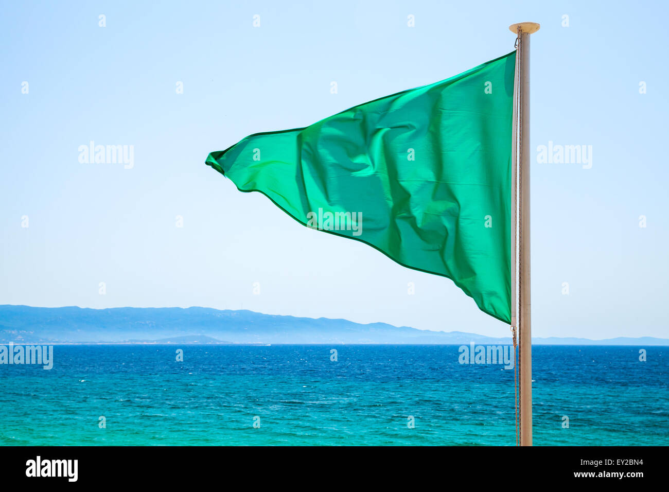 Bandiera verde sulla spiaggia e blu brillante sullo sfondo del mare, significa che il nuoto è consentito Foto Stock