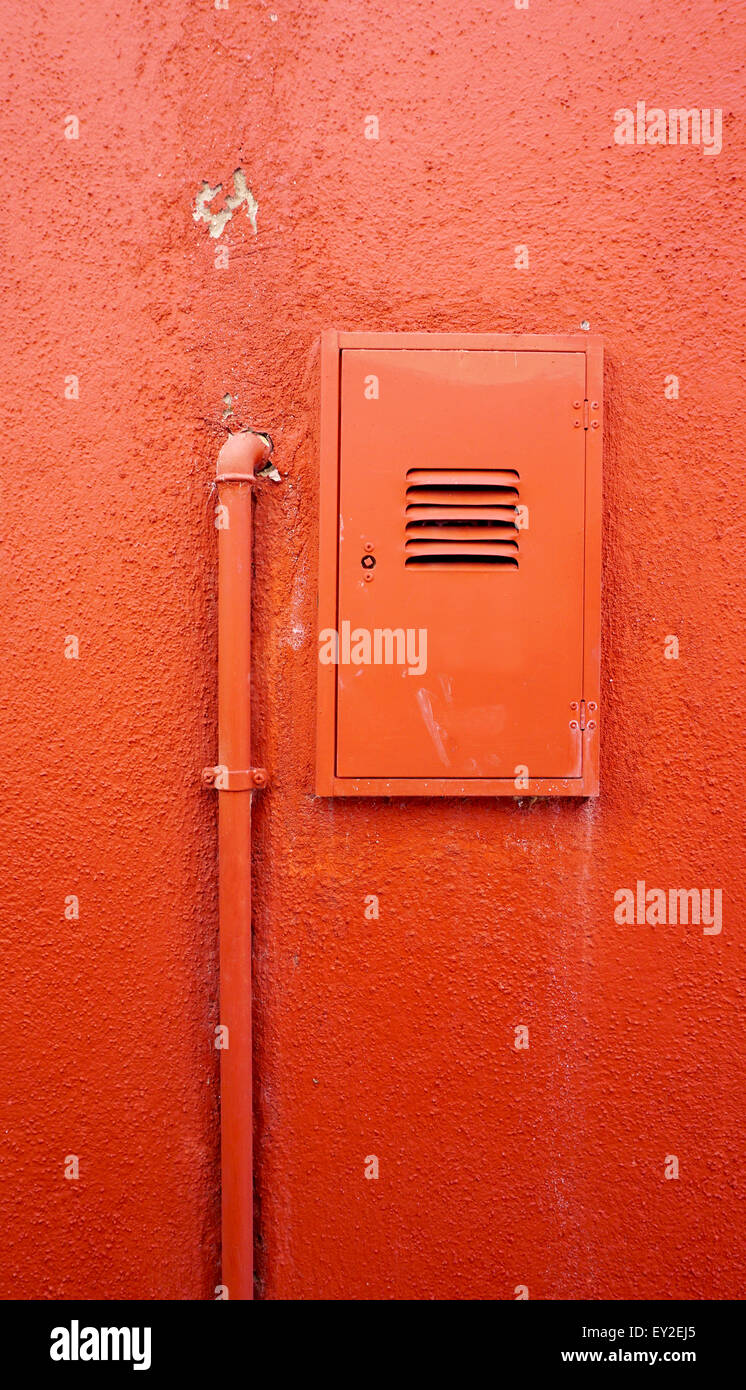 Verticale della canalizzazione metallica e la scatola elettrica sul colore arancione a parete in Burano Venezia Italia Foto Stock