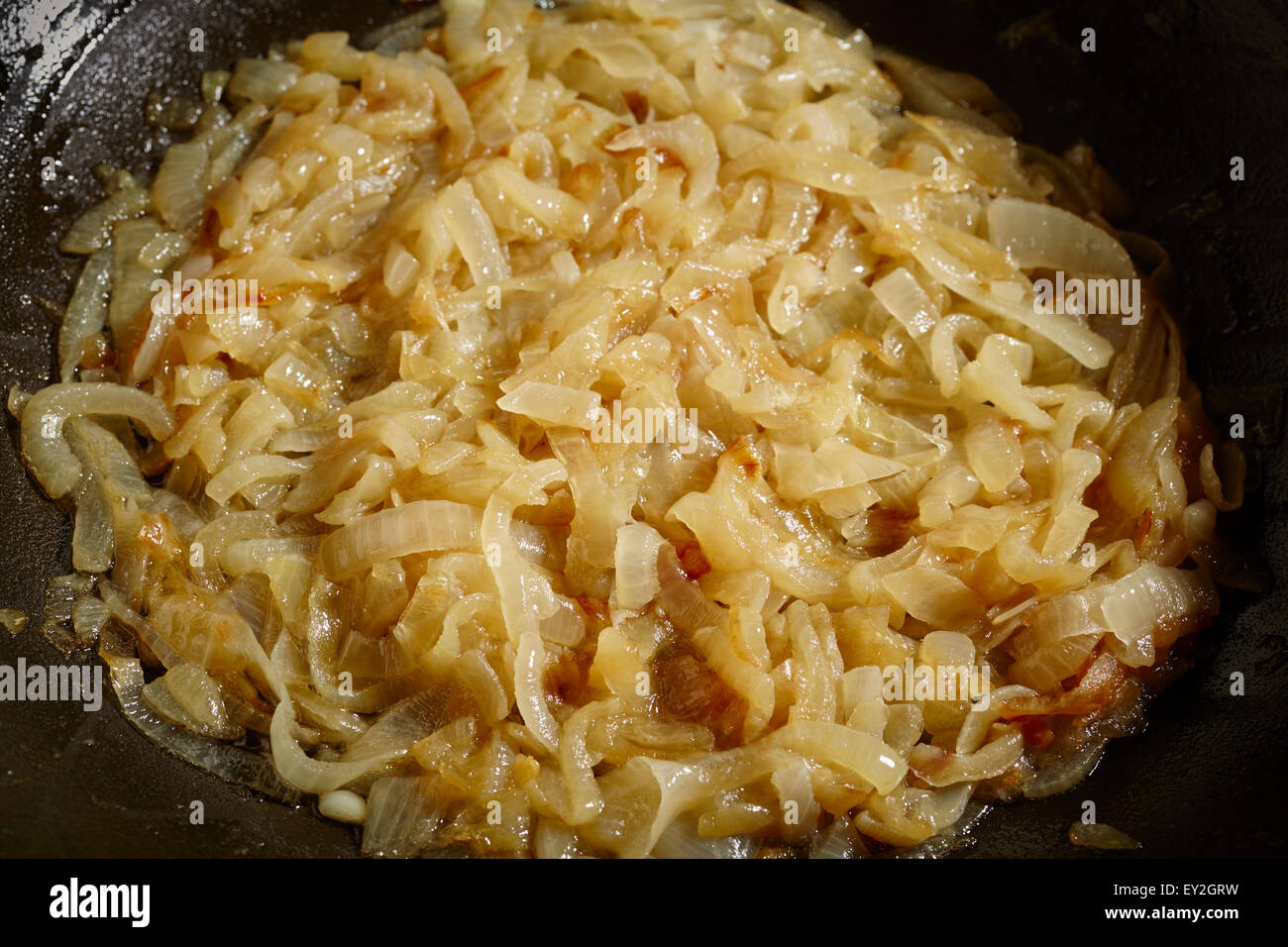 Le cipolle caramellate in un nero wok in acciaio Foto Stock