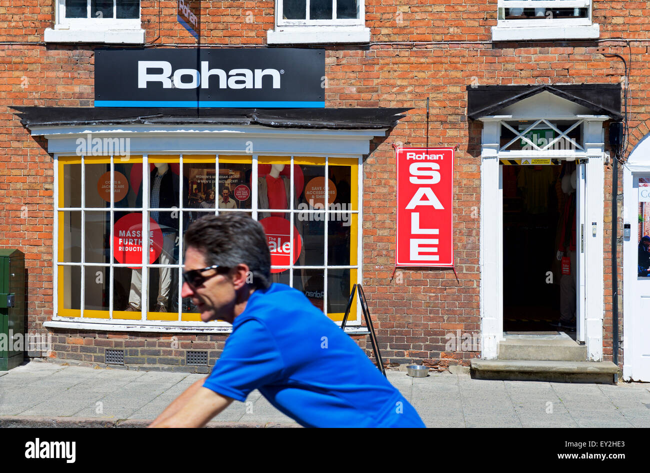 Uomo passato ciclismo Rohan abbigliamento outdoor shop, Stratford upon Avon, Warwickshire, Inghilterra, Regno Unito Foto Stock