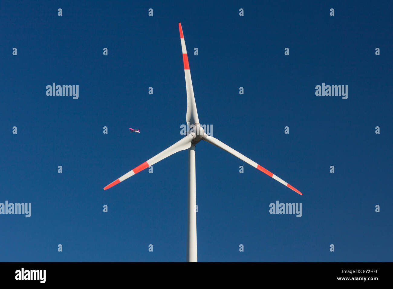 Aereo Jet visto attraverso le pale del rotore della turbina eolica contro il cielo blu Foto Stock