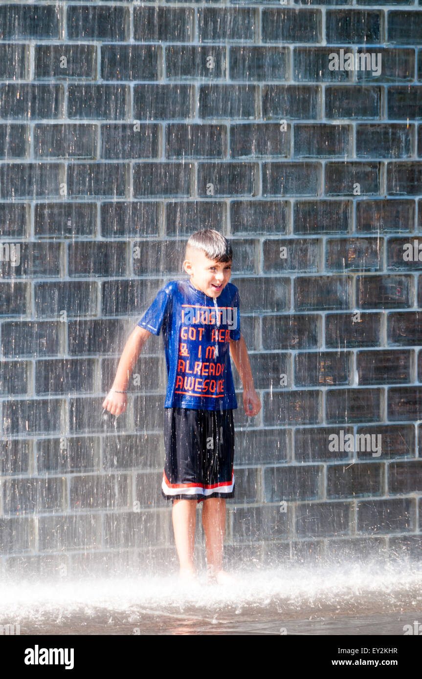 Un giovane ragazzo giocando nella corona Fontana nel Millennium Park di Chicago. Foto Stock