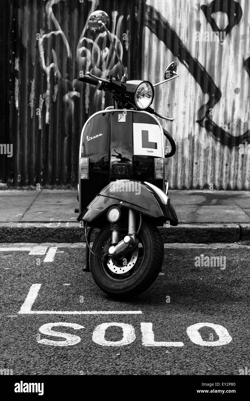 Un scooter Vespa parcheggiata in un motociclo bay con la parola 'solo' segnato sulla strada davanti a esso Foto Stock
