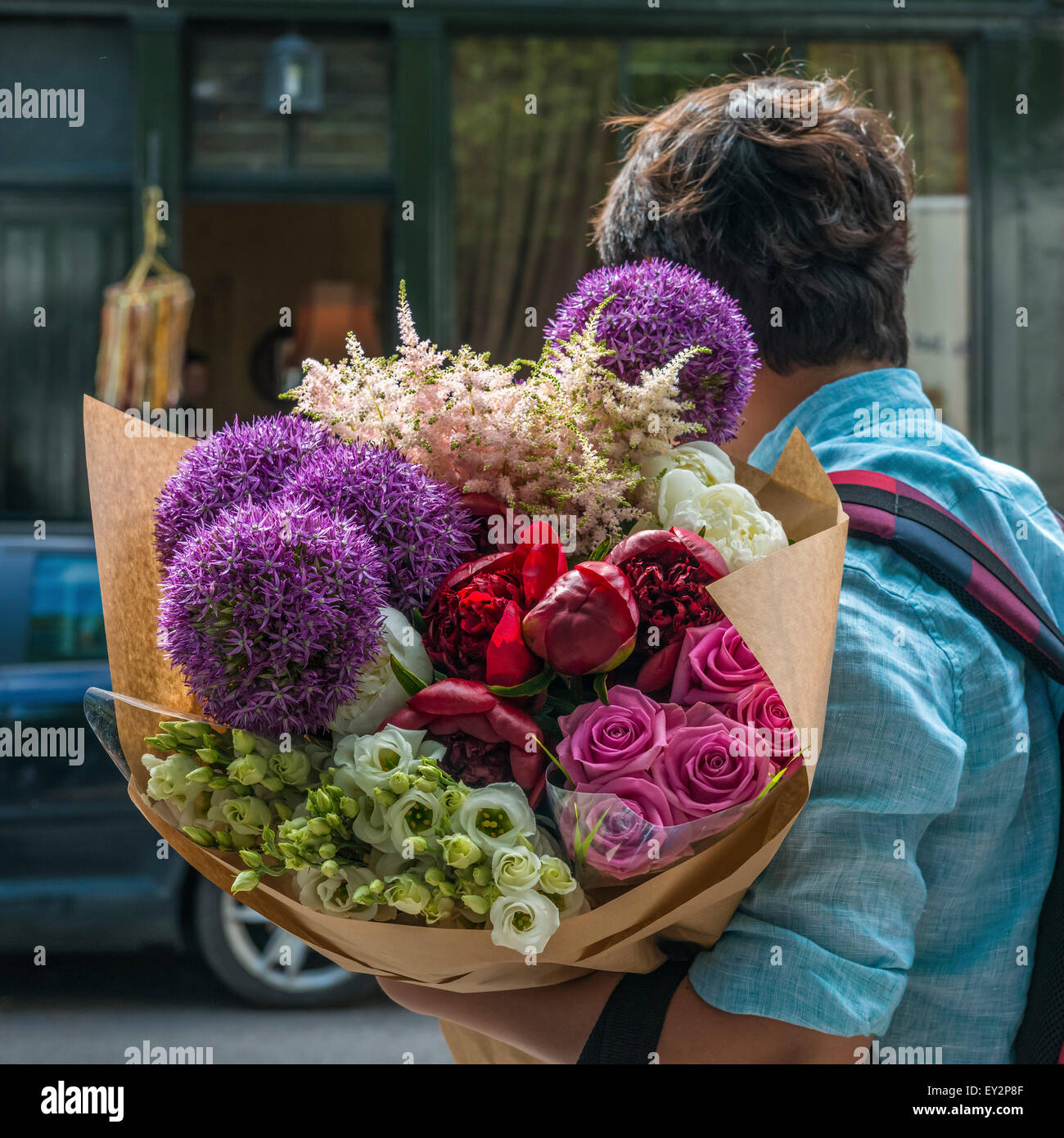 Una persona che porta un grande mucchio di coloratissimi fiori misti hanno acquistato presso la Columbia Road flower market di domenica mattina Foto Stock