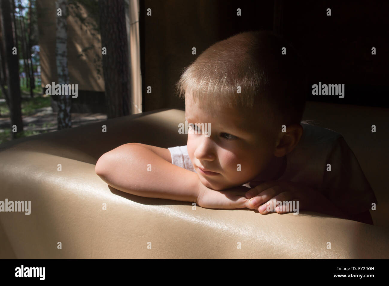Triste sconvolto in attesa noiosa premuto bambino (boy) vicino alla finestra di sera Foto Stock