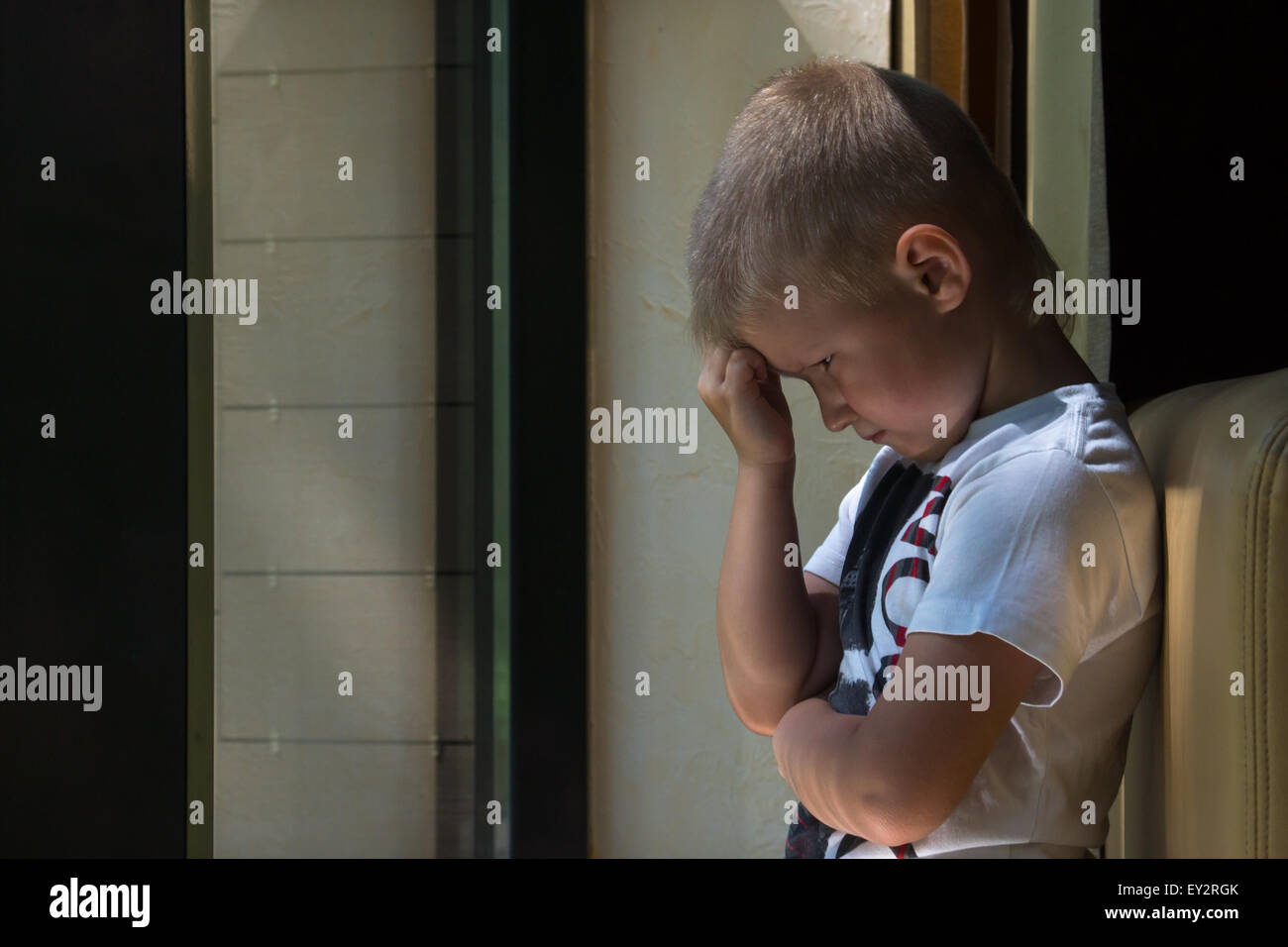 Triste sconvolto in attesa noiosa premuto bambino (boy) vicino a una finestra Foto Stock