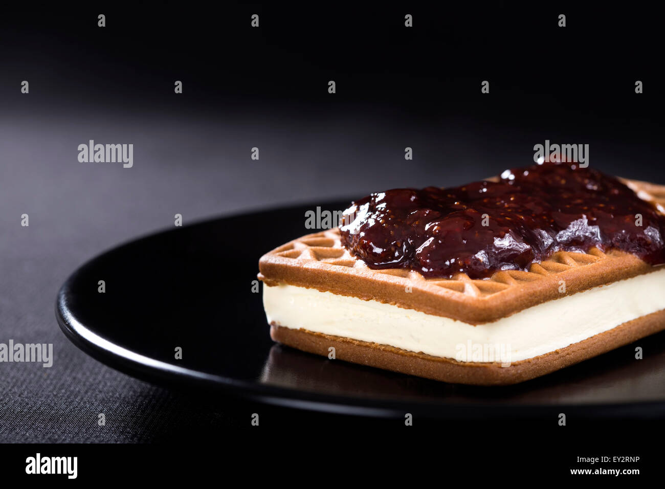 Ice Cream Sandwich con confettura di fragole su una piastra scuro Foto Stock