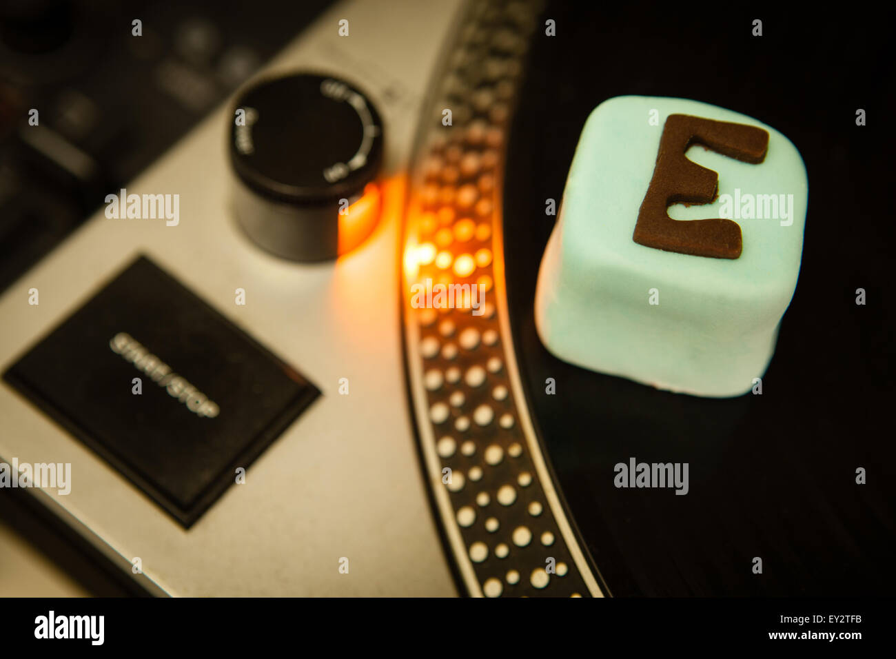 Una torta con e per ecstasy scritto su di esso seduti su un DJ deck di registrazione Foto Stock