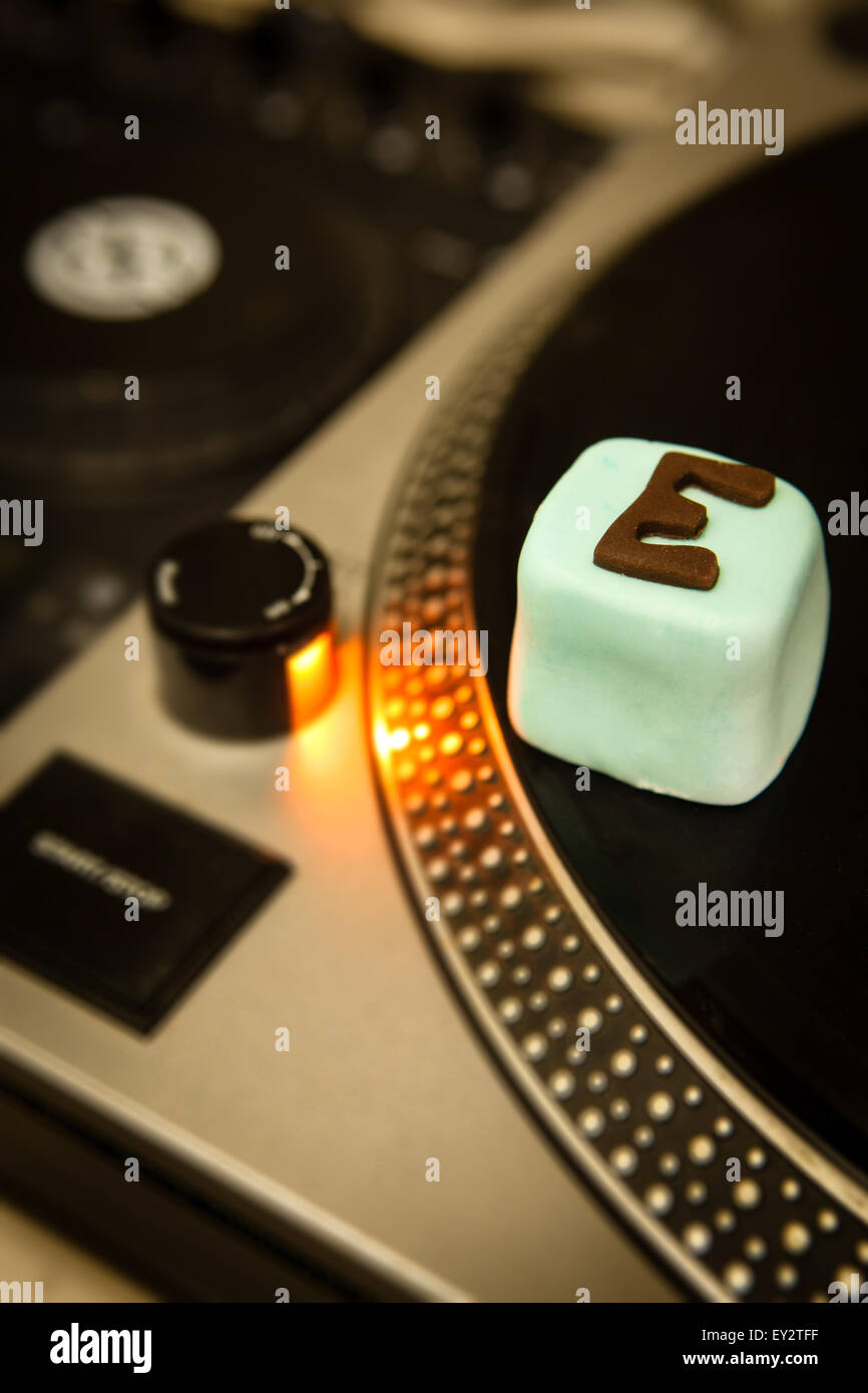 Una torta con e per ecstasy scritto su di esso seduti su un DJ deck di registrazione Foto Stock