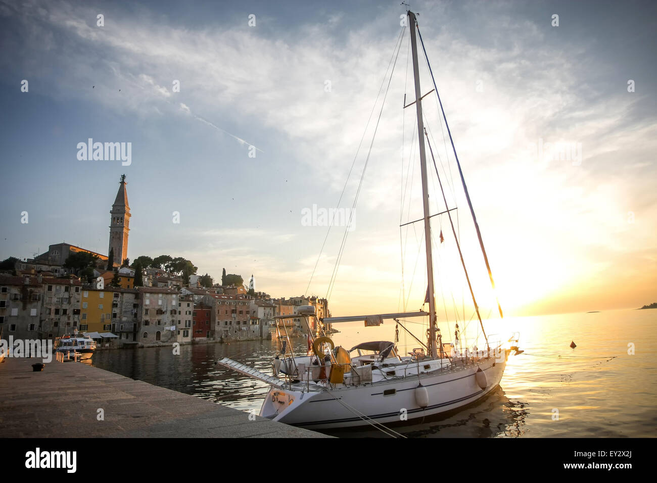 Una barca a vela ancorata al molo di fronte al nucleo storico della città con la Santa Eufemia chiesa al tramonto a Rovigno Croazia. Foto Stock