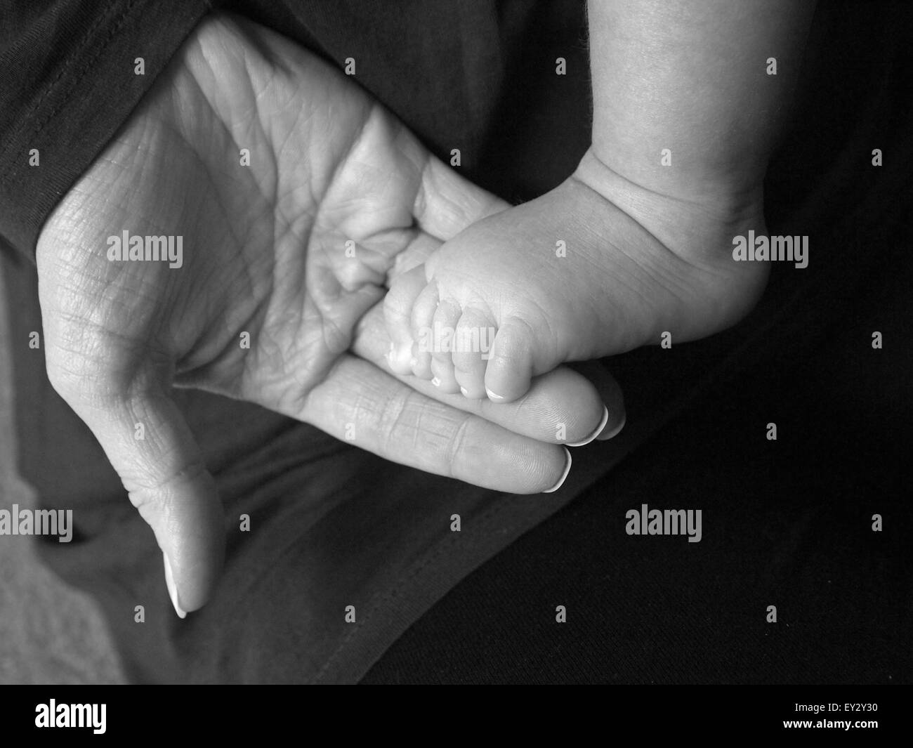 Immagine in bianco e nero della madre e del bambino. Madre di supporto a mano del bambino in piedi, mostrando palmo e le dita dei piedi del bambino. Foto Stock