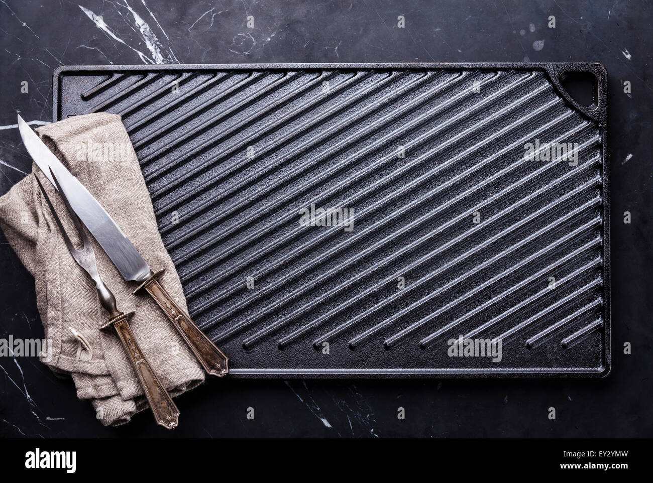 Ghisa nera superficie grill e il coltello e forchetta carving impostato su Sfondo marmo Foto Stock
