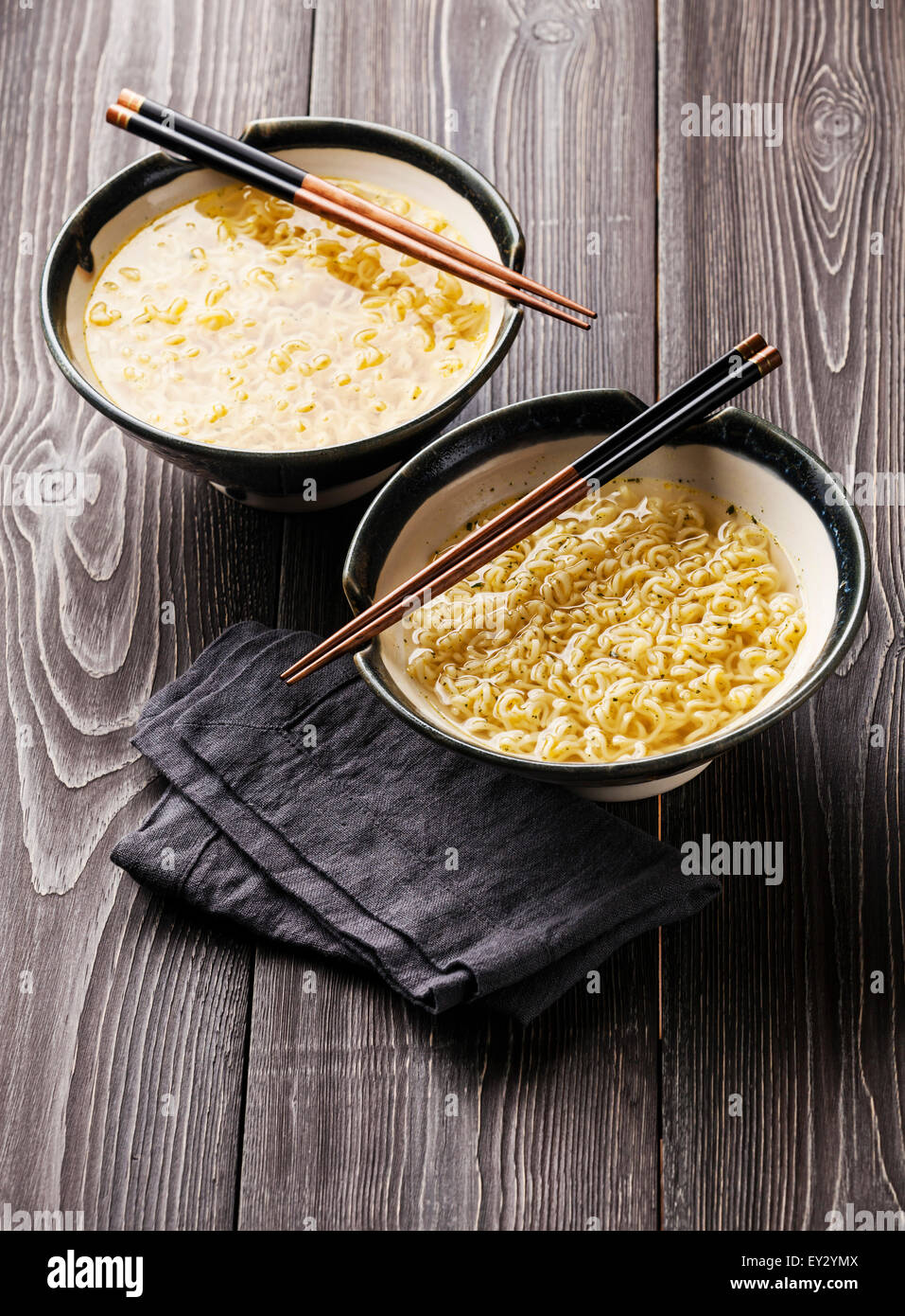 Asian Miso di spaghetti ramen e bacchette in ciotole in grigio sullo sfondo di legno Foto Stock