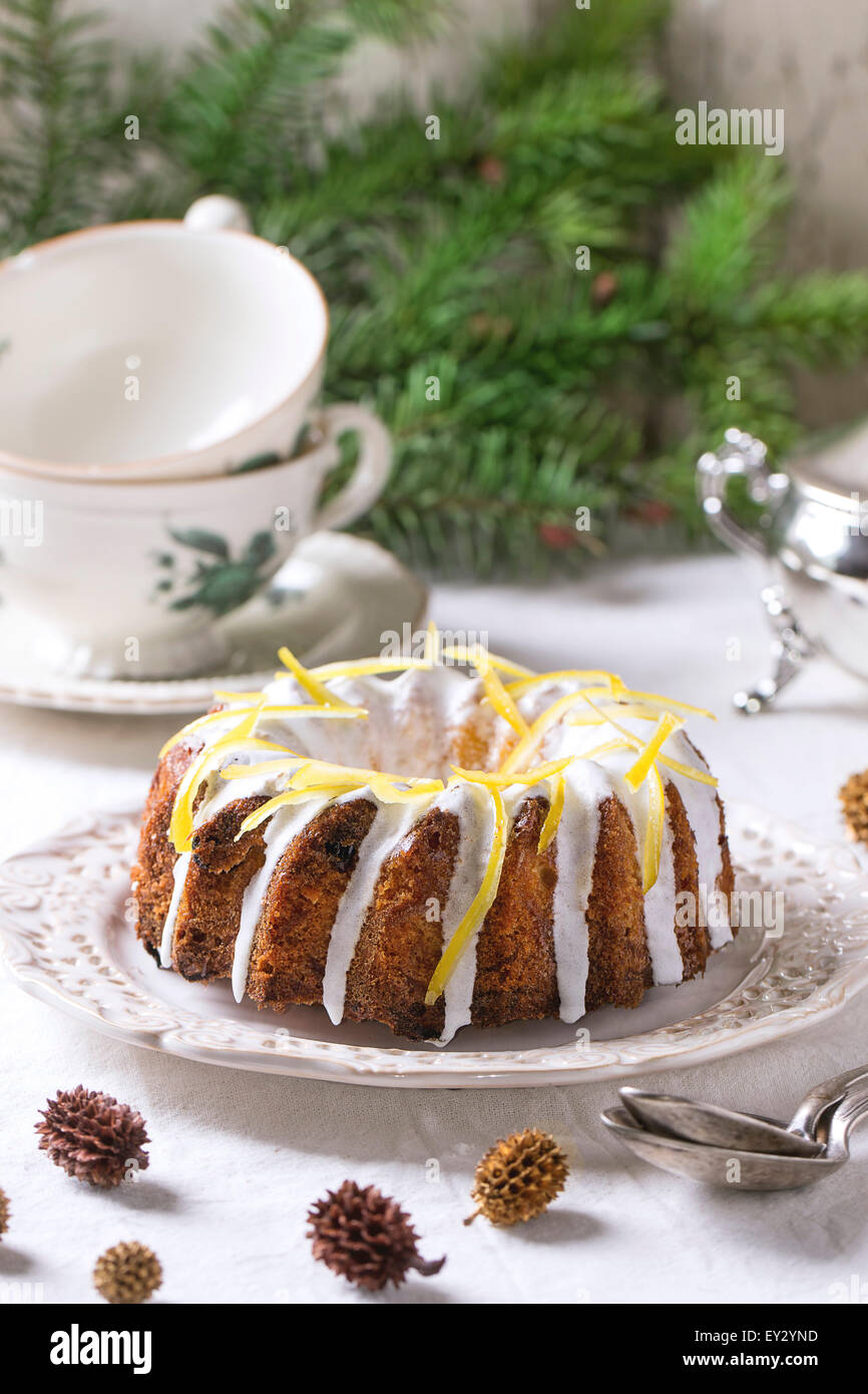 Natale torte fatte in casa con la glassa e la scorza di limone servita con albero di natale rami, vintage vasellame e decor e sopra il tavolo Foto Stock