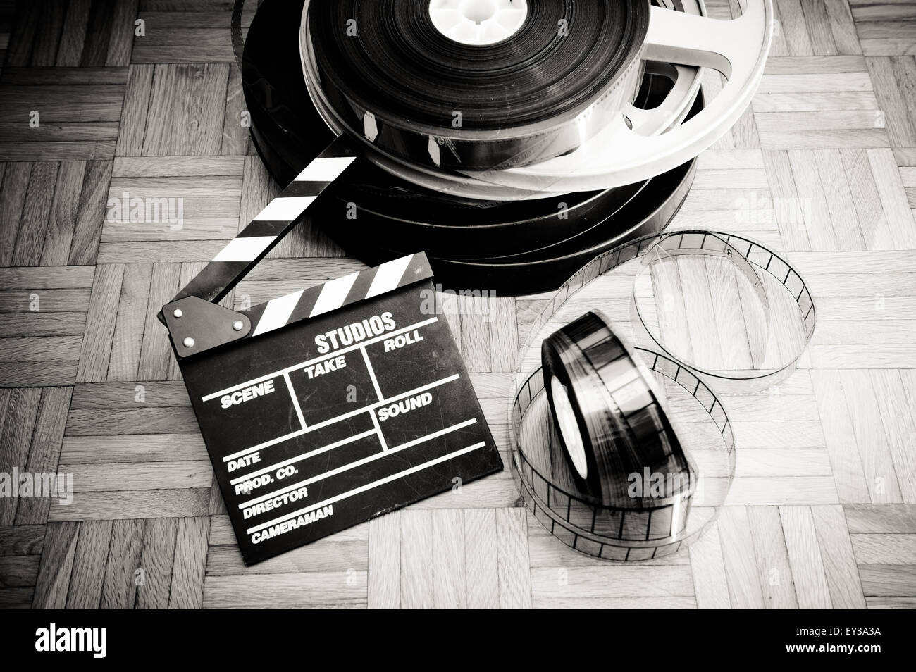 Film Cinema battaglio board e bobina di pellicola sul pavimento in legno vintage in bianco e nero Foto Stock