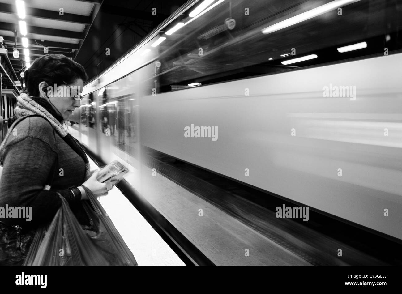 Una donna che ascolta la sua musica in piedi su una piattaforma mentre un treno arriva alla stazione centrale di Sydney nel nuovo Galles del Sud, Australia Foto Stock