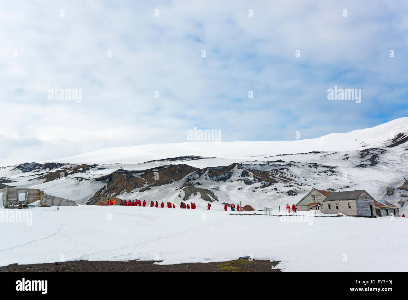 Gruppo di persone nei pressi di una base sull isola Deception, montagne coperte di neve in background. Foto Stock