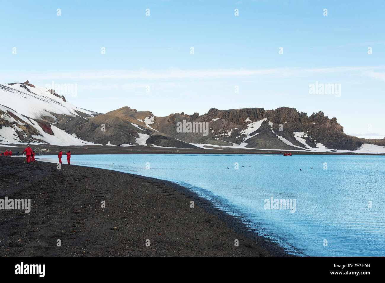 Gruppo di persone su una spiaggia sull isola Deception, montagne coperte di neve in background. Foto Stock