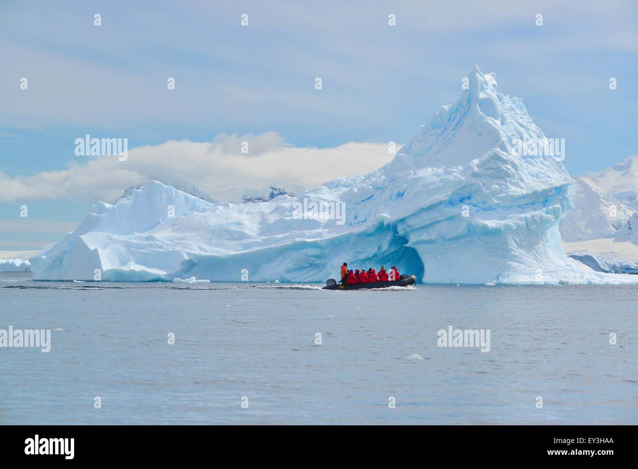 Vista di un gruppo di persone in una barca di gomma in prossimità di un iceberg torreggianti in Antartide. Foto Stock