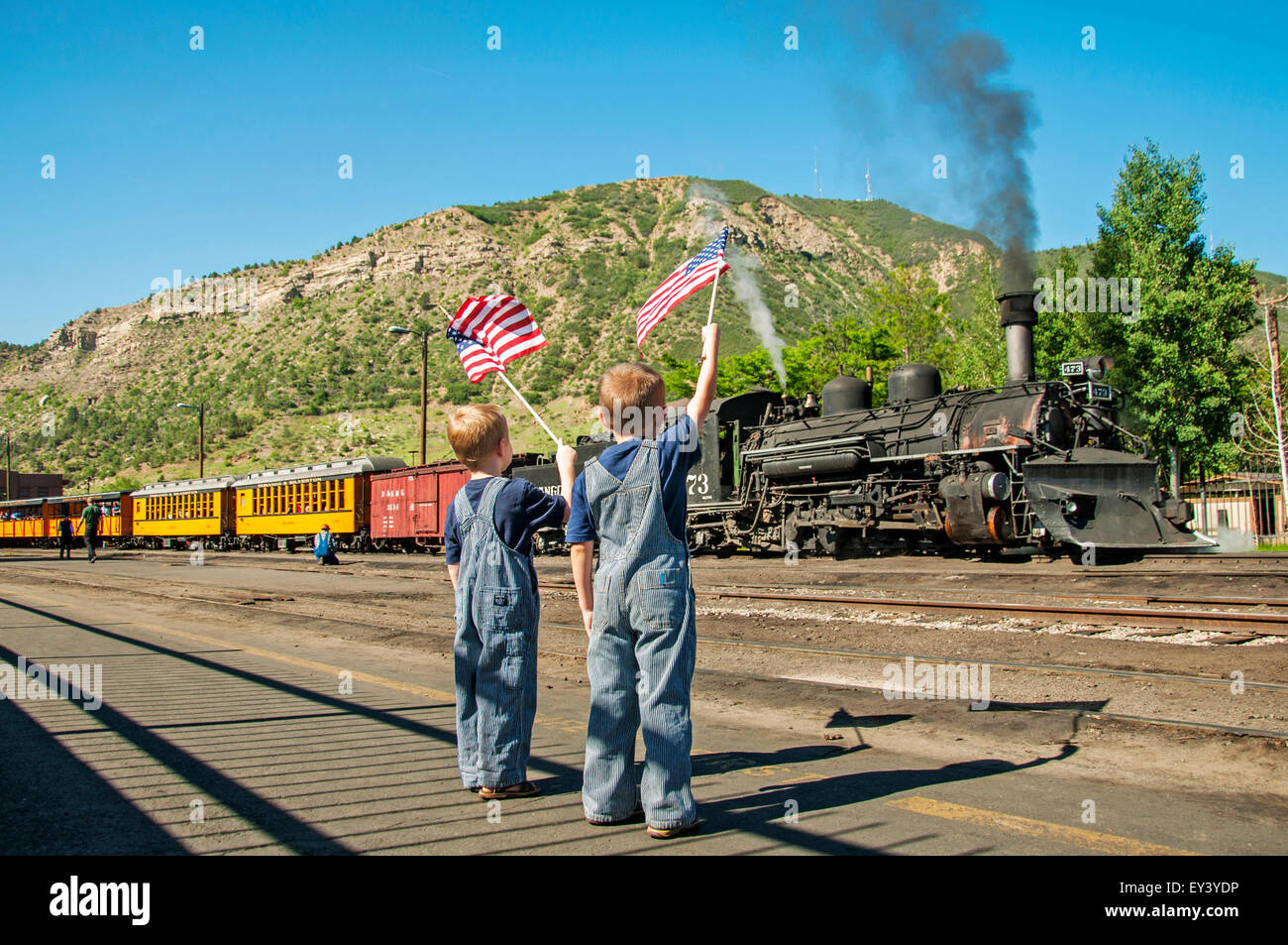 Ragazzi wave bandierine americane al treno in partenza Foto Stock