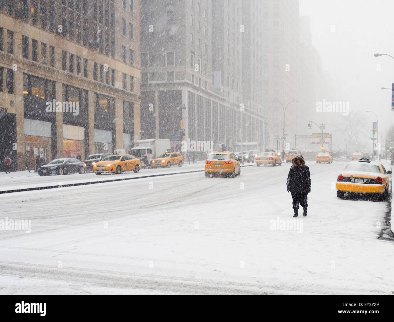 Uomo che cammina in una città nella neve durante una bufera di neve, giallo taxi sulla strada. Foto Stock