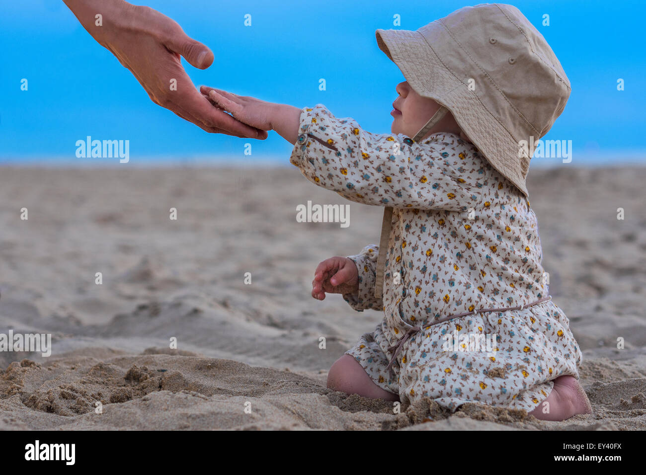 Padre di raggiungere la sua mano a sua figlia in spiaggia Foto Stock