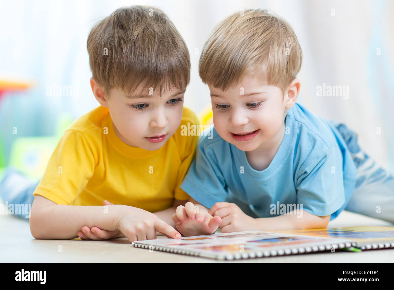 Bambini letto insieme libro che giace sul pavimento in vivaio Foto Stock