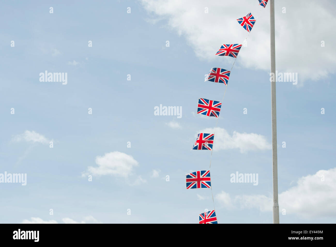 Union Jack flag bunting su una bandiera pole contro un cielo blu Foto Stock