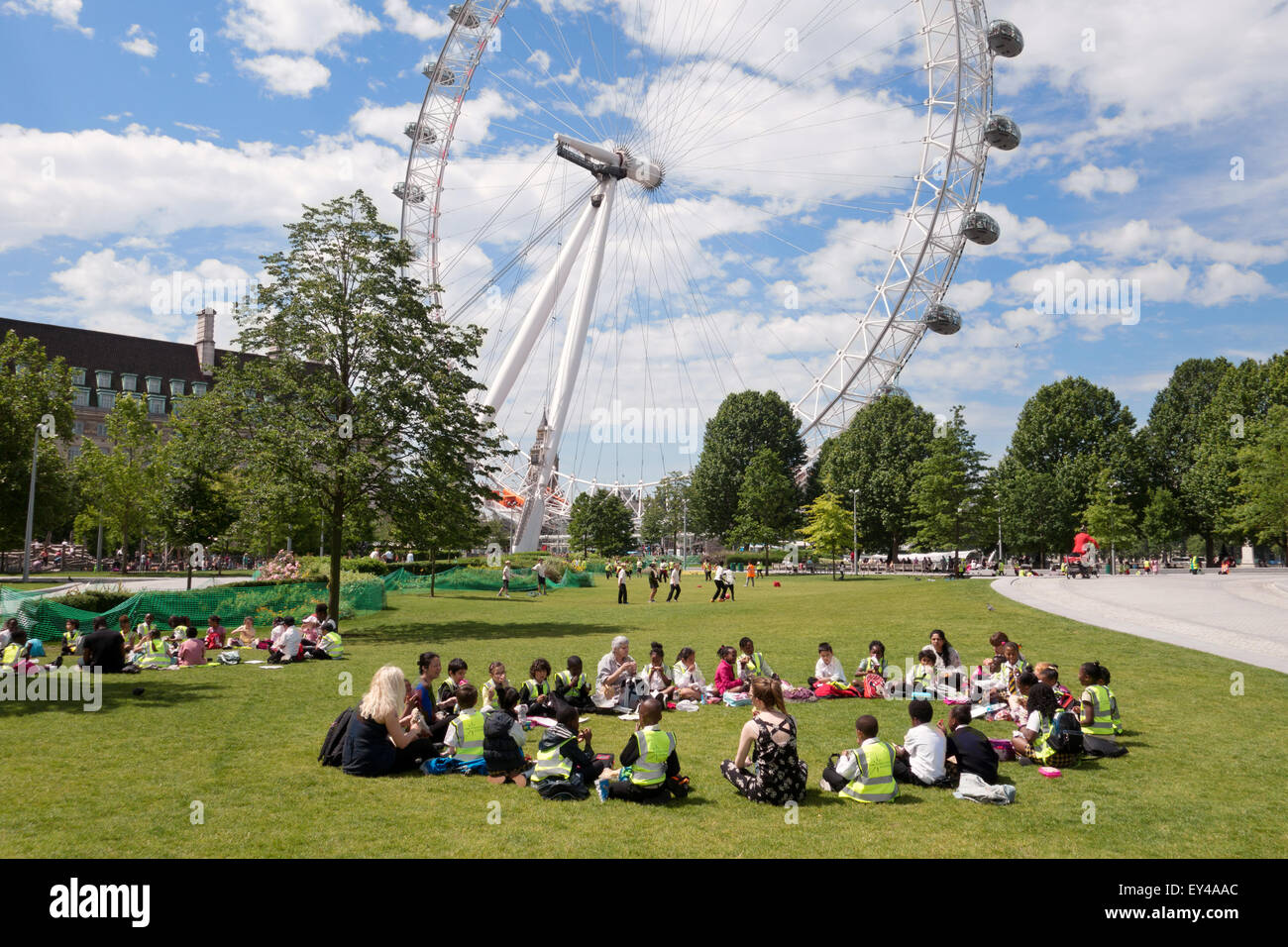 I bambini in gita scolastica in seduta Jubilee Gardens vicino al London Eye in una giornata di sole in giugno, Jubilee Gardens, London REGNO UNITO Foto Stock