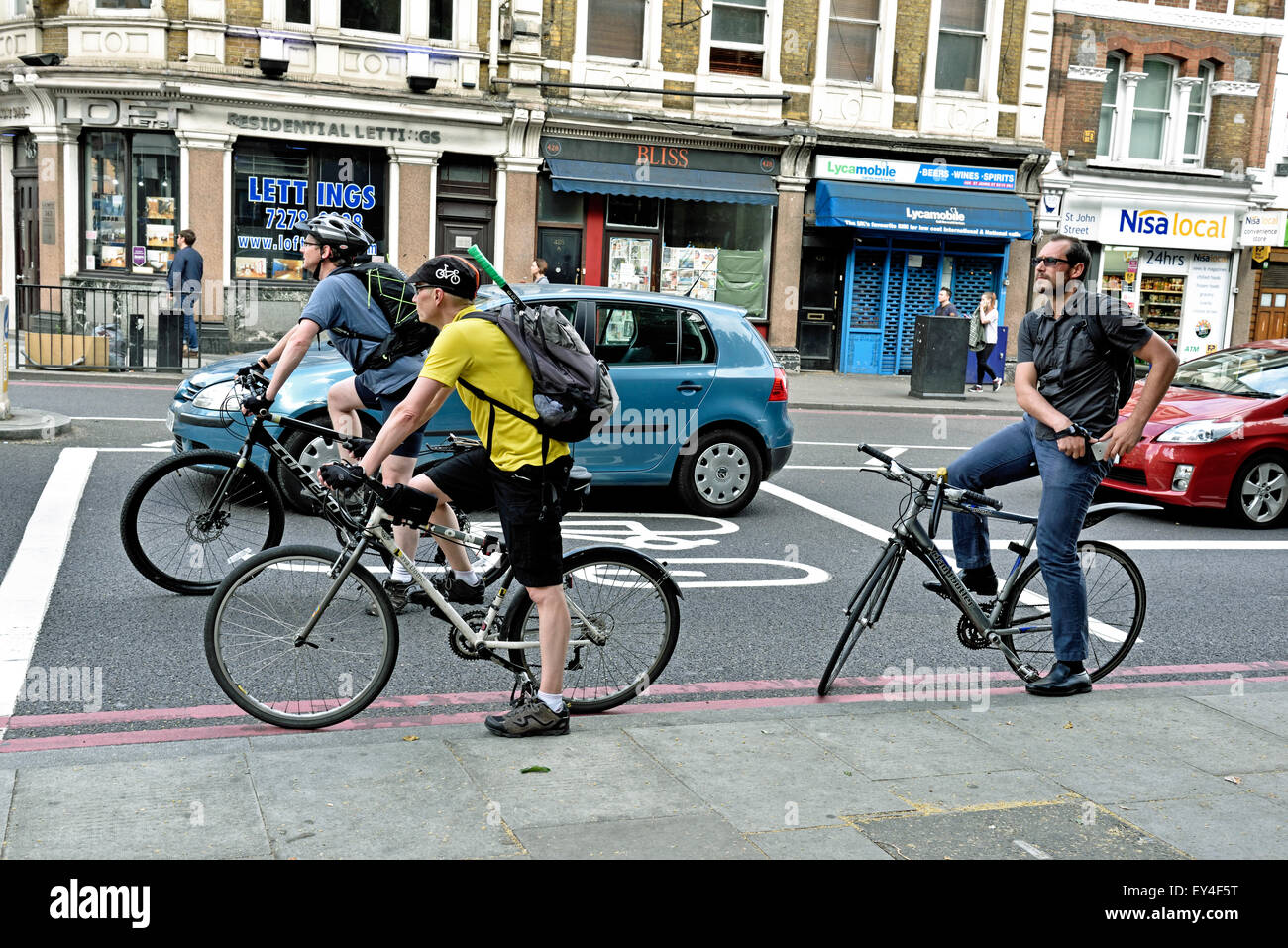 I ciclisti di " commuters " in anticipo la corsia di arresto al fianco di illegalmente posto auto, Angelo, London Borough di Islington, England Regno Unito Foto Stock