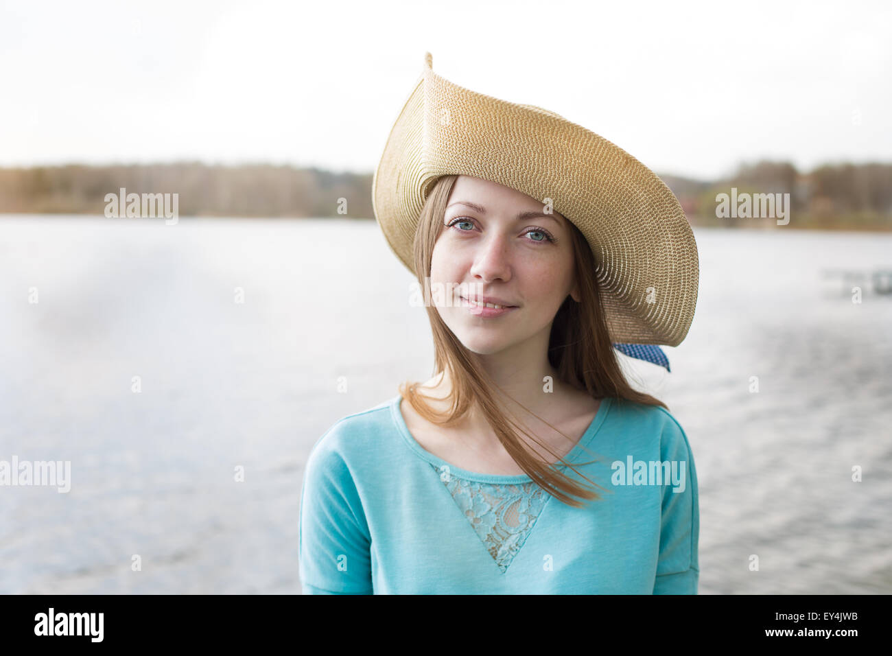 Freckled ragazza in hat guardando la fotocamera e sorridente sul lago di sfondo Foto Stock