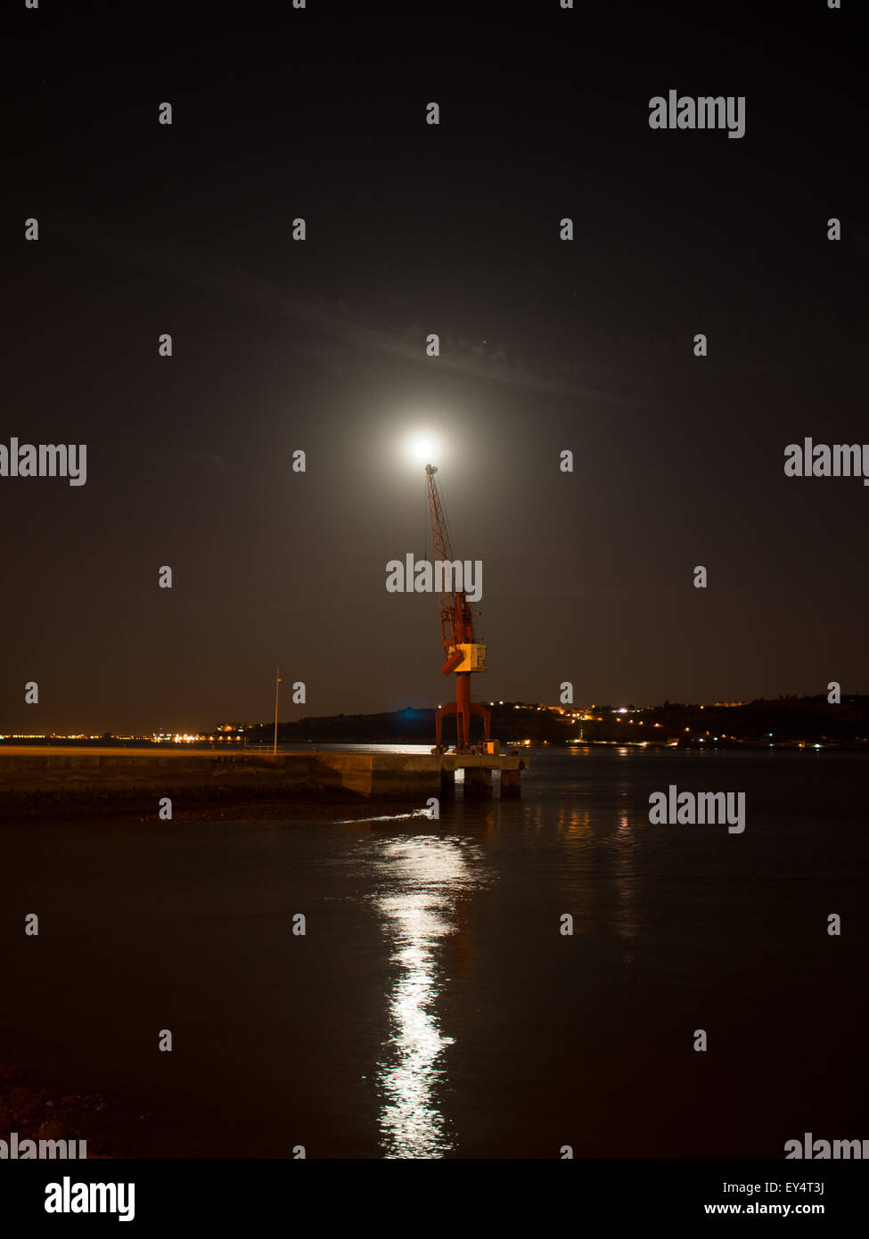 Luna piena sopra una gru portuale da Lisbona il fiume Tago di notte Foto Stock