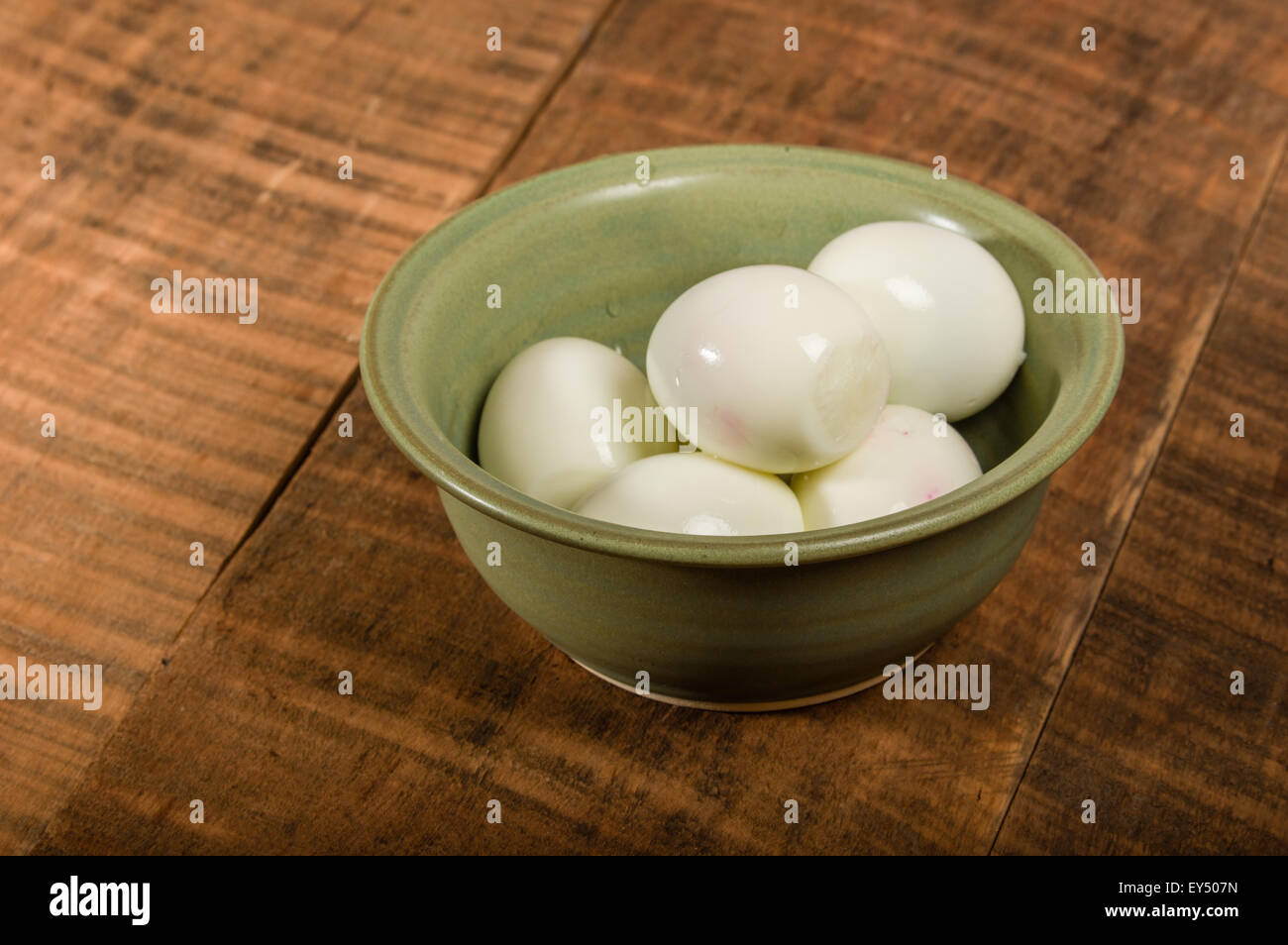 Ciotola verde sul tavolo con sbucciate le uova sode Foto Stock