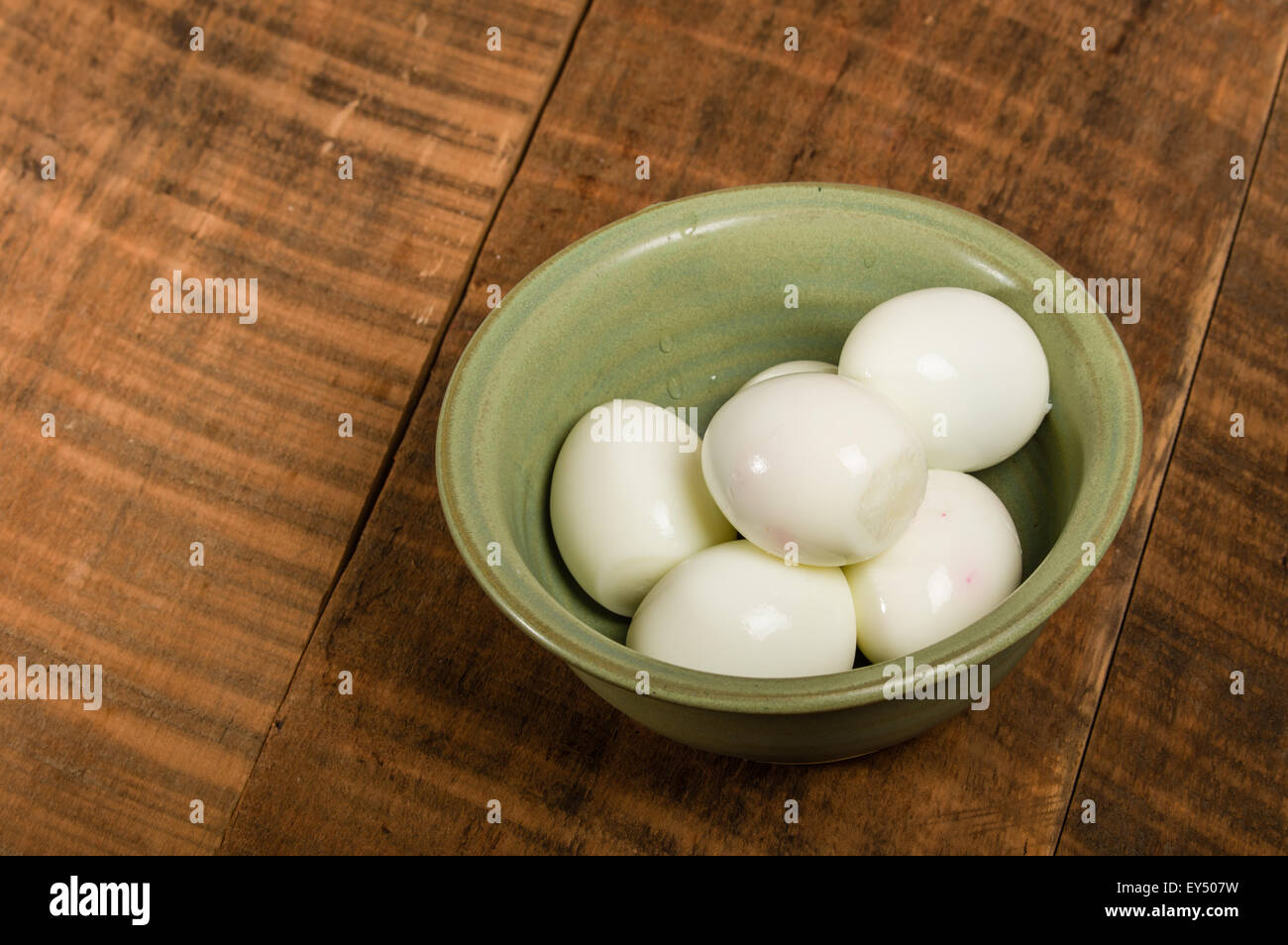Ciotola verde sul tavolo con sbucciate le uova sode Foto Stock