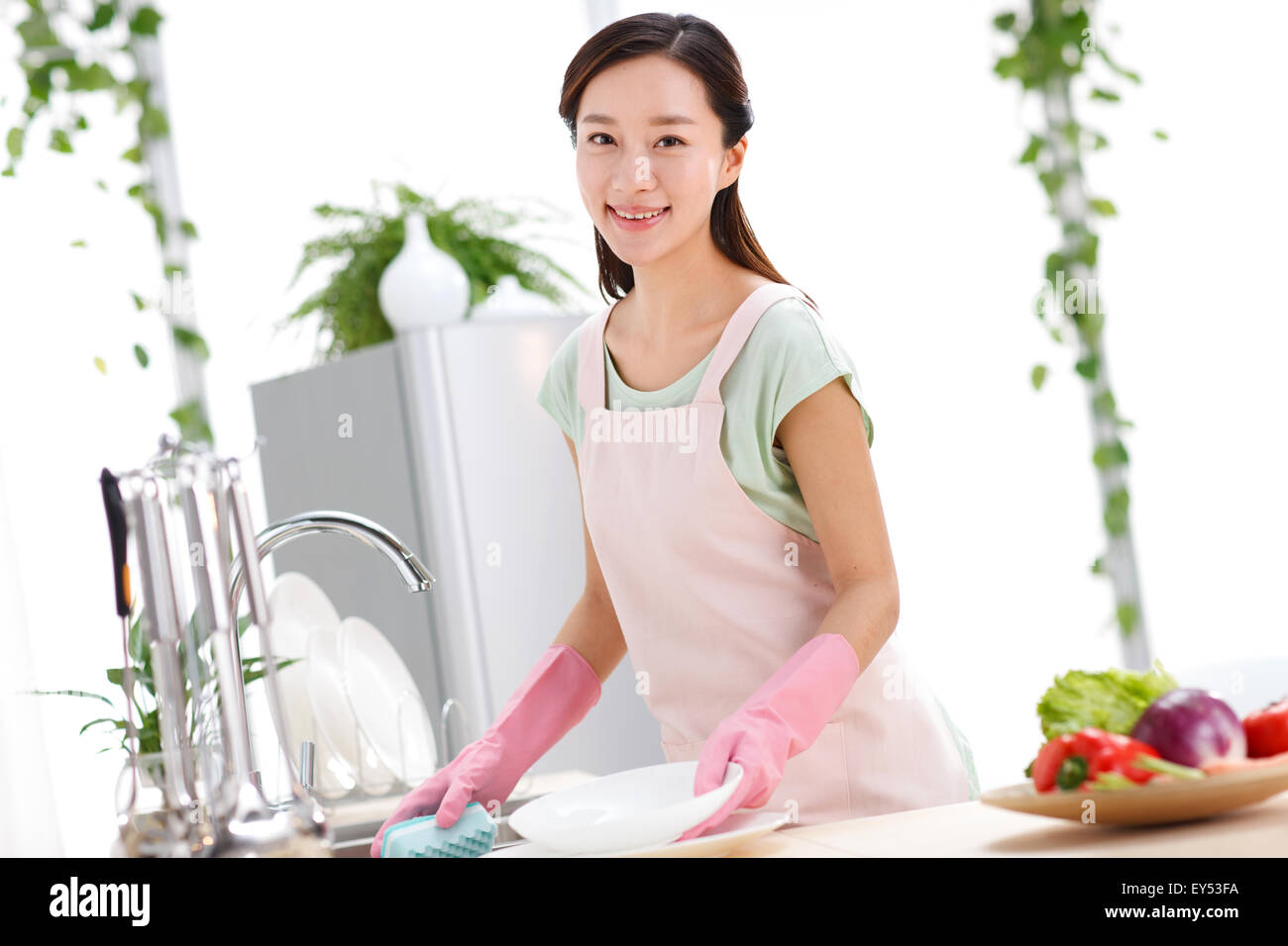 Giovane donna il lavaggio dei piatti in cucina Foto Stock