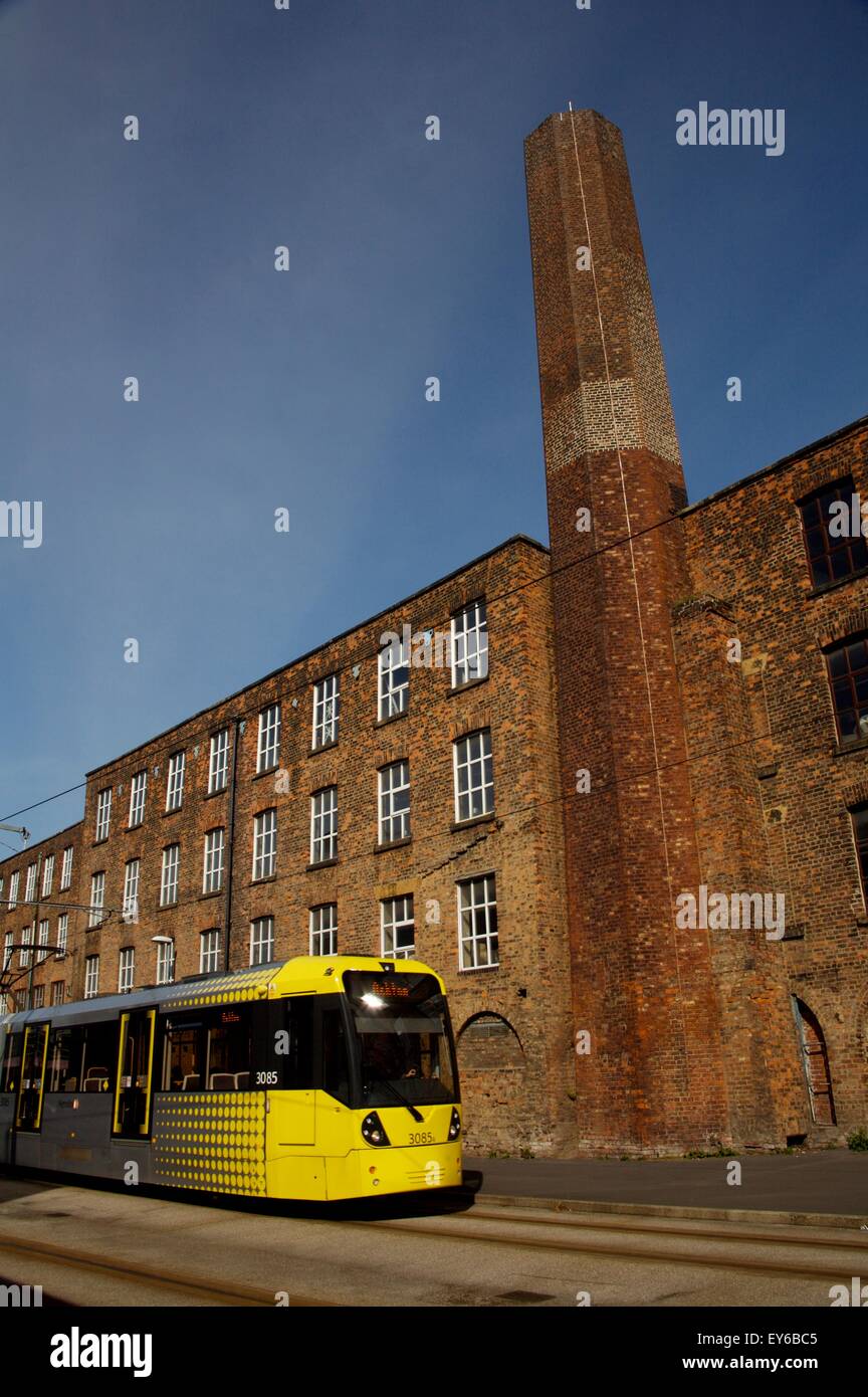 Moderno tram passando il patrimonio industriale - ex mulino - in Manchester Foto Stock