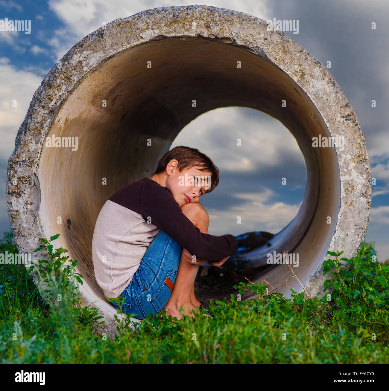 Senzatetto ragazzo adolescente triste seduta nel tubo di calcestruzzo agoraphob Foto Stock