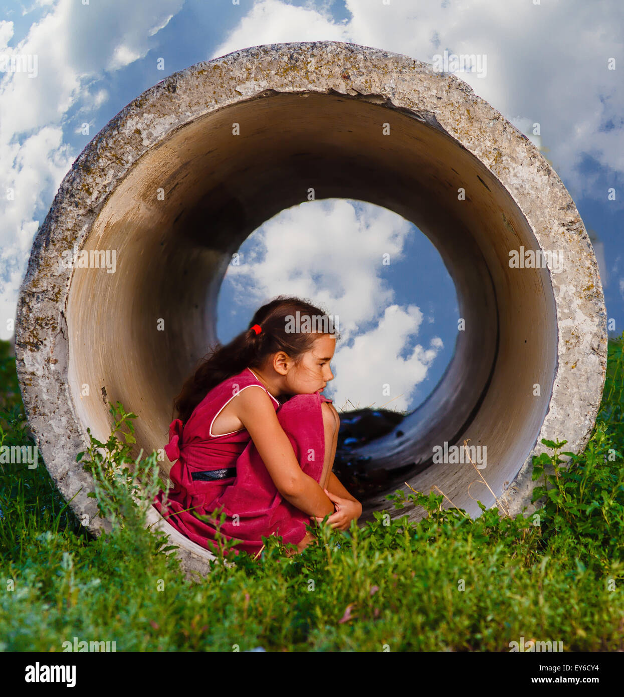 Senzatetto ragazza adolescente si siede sul suo haunches nel tubo di calcestruzzo Foto Stock