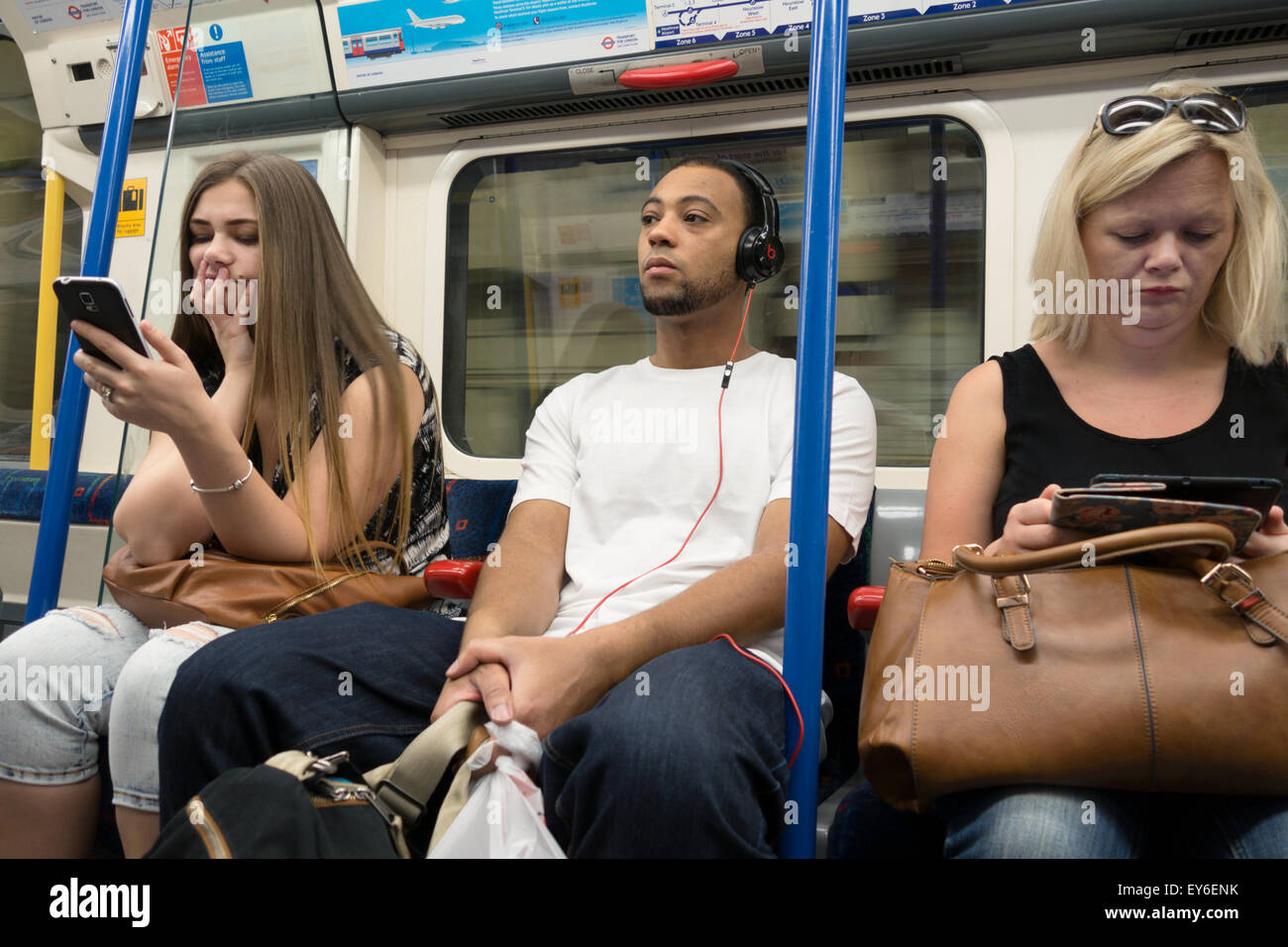 I passeggeri di una metropolitana treno tubo utilizzando moderne tecnologie tra cui il telefono cellulare, e lettori e musica. London REGNO UNITO Foto Stock