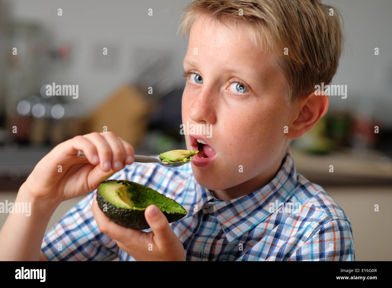 Un bambino di mangiare un avocado con un cucchiaio come snack sani Foto Stock