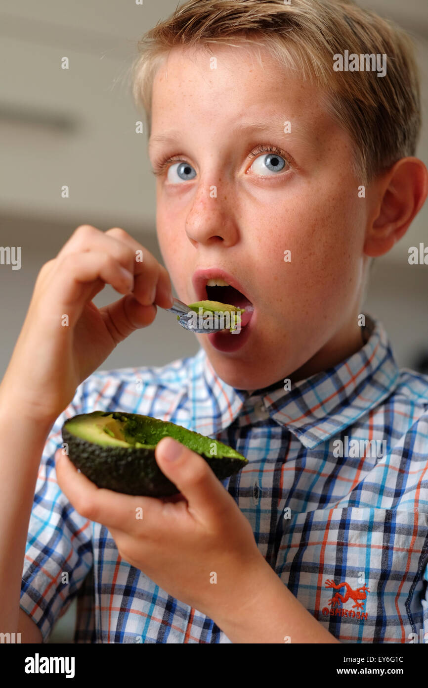 Un bambino di mangiare un avocado con un cucchiaio come snack sani Foto Stock