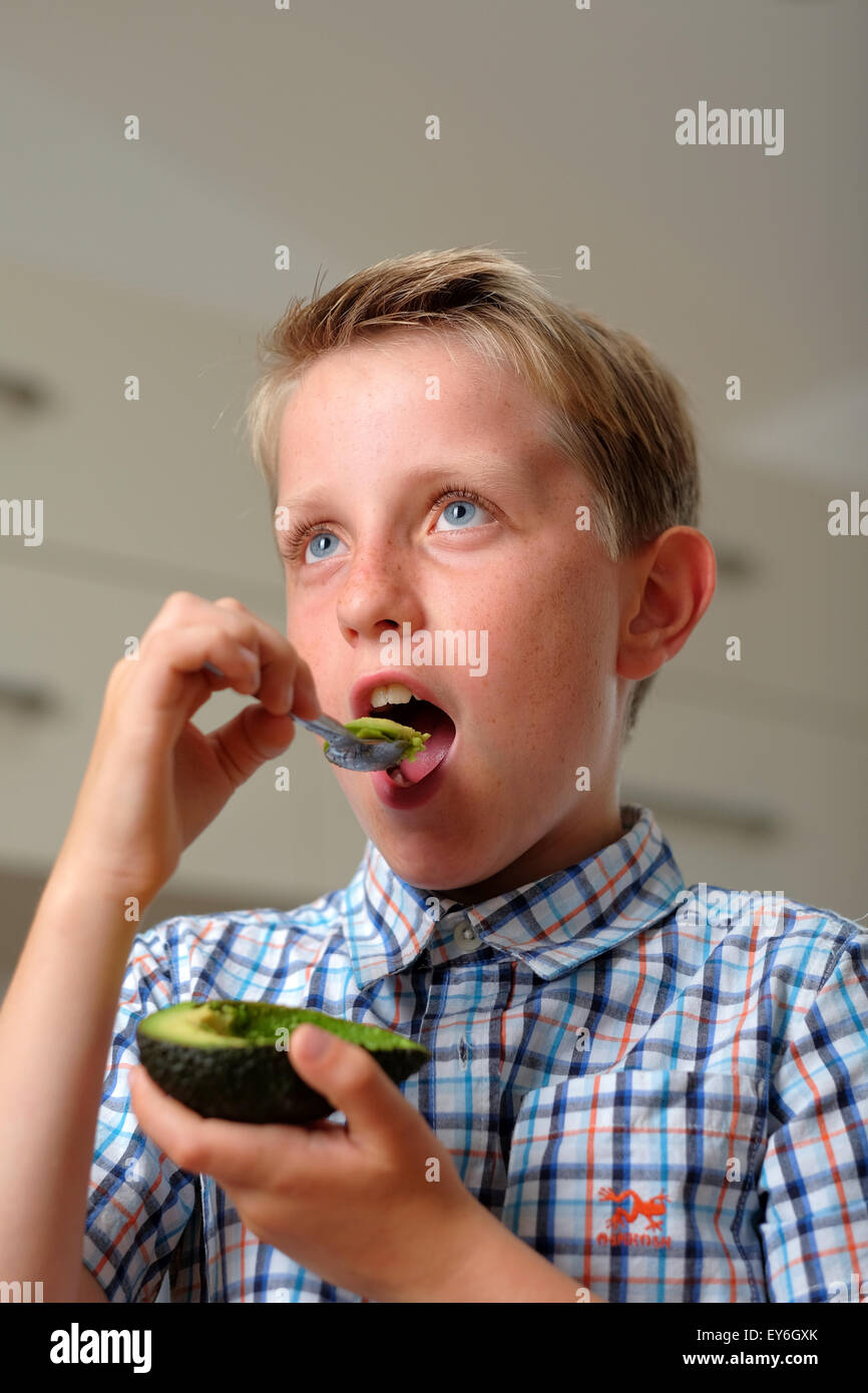 Un bambino di mangiare un avocado con un cucchiaio come snack sani Foto Stock
