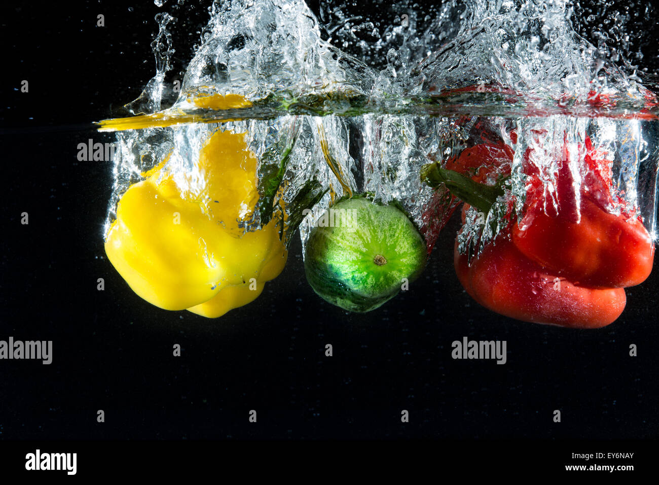 Verdure in diversi colori, giallo e rosso, gettati in acqua per creare effetto splash Foto Stock