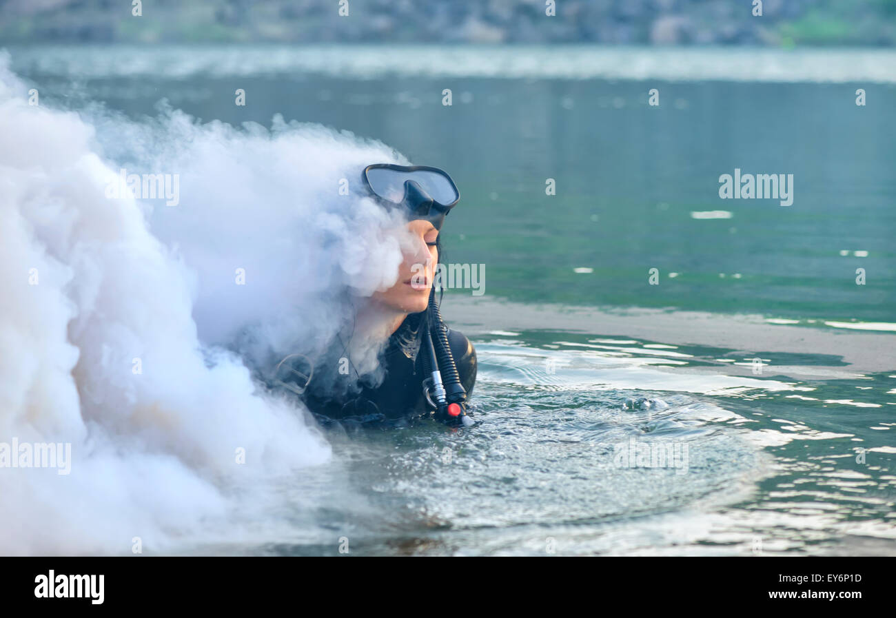 Donna subacqueo in acqua avvolta nel fumo Foto Stock