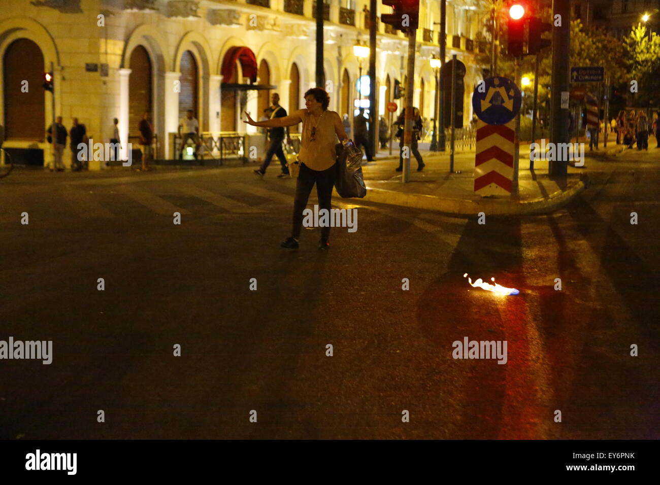 Atene, Grecia. 22 Luglio, 2015. Una donna passa dai resti di un ardente Molotov cocktail presso la protesta contro la seconda tranche dei greco-misure di austerità in Atene. I Greci hanno protestato fuori del parlamento greco come la seconda tranche delle nuove misure di austerità sono state discusse in Parlamento. Le nuove normative includono un diritto e riforma bancaria. La protesta è rimasta per lo più tranquilla con un paio di tafferugli tra la polizia e gli anarchici alla fine. © Michael Debets/Pacific Press/Alamy Live News Foto Stock