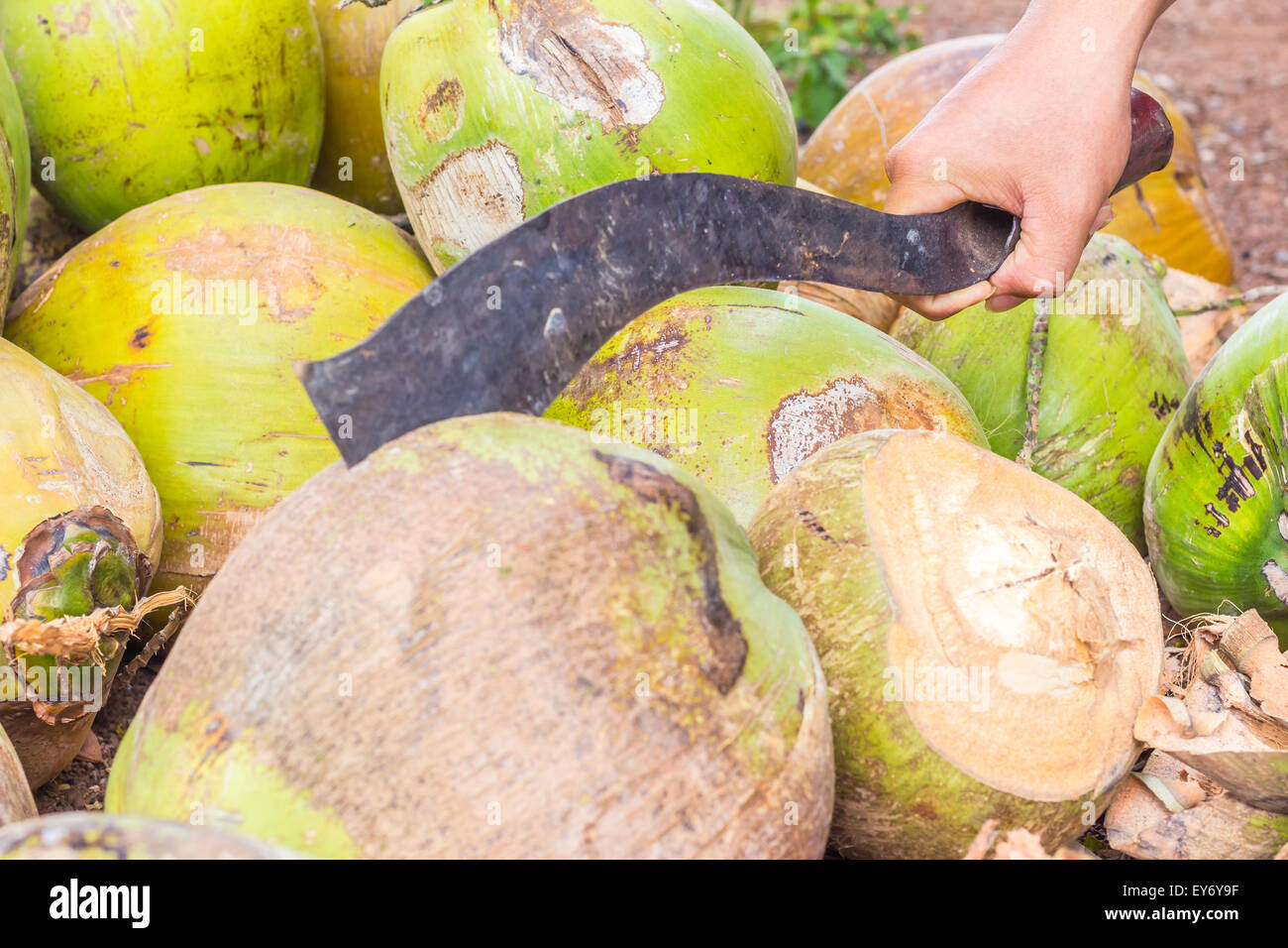 L'uomo,mostra solo la mano, tritare il cocco dal coltello di grosse dimensioni Foto Stock