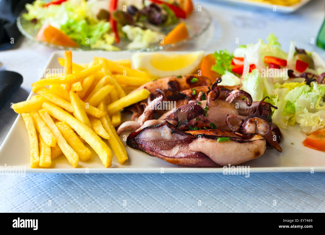 Calamari alla griglia con patate fritte e insalata mista Foto Stock