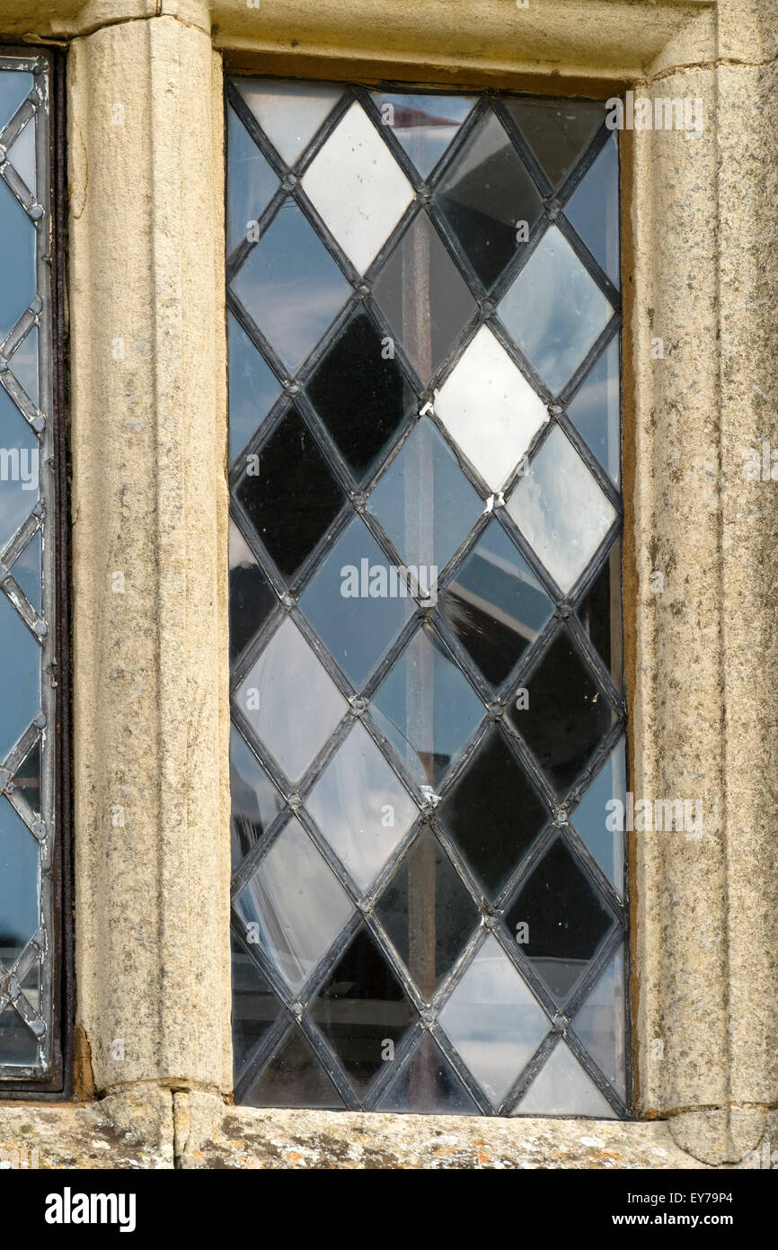 Riflessi in lastre di vetro a forma di diamante di una vecchia finestra con piombo con mulloni di pietra, Rockingham, Northamptonshire, Inghilterra, UK Foto Stock