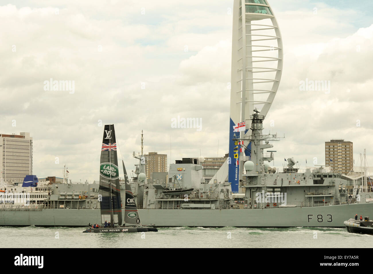 Portsmouth, Regno Unito. 23 Luglio, 2015. Il passato di vela presso la Coppa America World Series di Portsmouth. Sir Ben Ainslie al timone di Land Rover BAR, il Challenger del Regno Unito al fianco di HMS St Albans come lasciano il porto di Portsmouth. Credito: Rob Wilkinson/ Alamy Live News Foto Stock