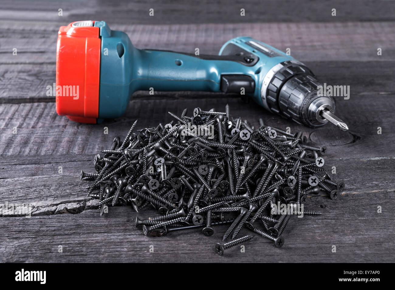 Pila di viti nere e cacciavite closeup su sfondo di legno Foto Stock